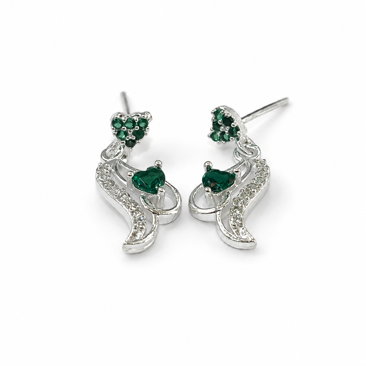 A pair of silver-toned dangle earrings with heart-shaped green gemstone accents and small clear stones, shown on a plain white background.
