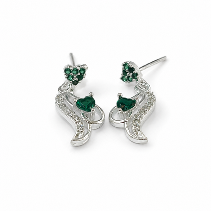 A pair of silver-toned dangle earrings with heart-shaped green gemstone accents and small clear stones, shown on a plain white background.