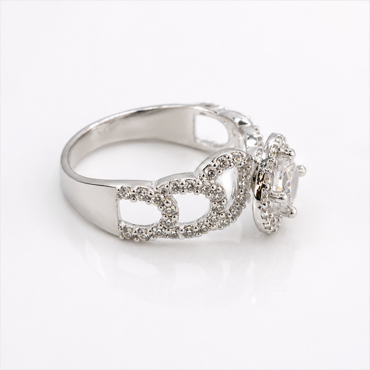 A silver-tone ring featuring a crown motif paved with small clear stones, with a larger clear central gemstone in a halo setting, shown on a white background.