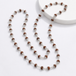 A beaded necklace with alternating brown textured round beads and silver metallic spacer beads, displayed on a clean white background with a white circular pedestal.